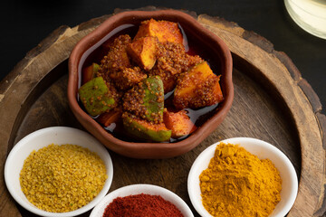 Homemade Mango Pickle or aam ka achar Kairi Loncha stored or preserved in China clay pot with Ingredients.