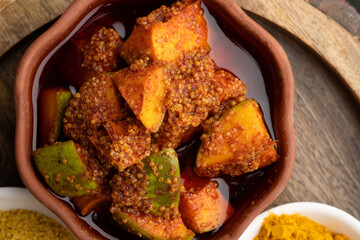 Homemade Mango Pickle or aam ka achar Kairi Loncha stored or preserved in China clay pot with...