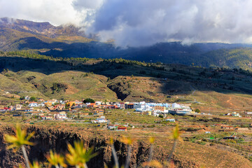 Fototapeta na wymiar Sweeping view of a mountain village in Tenerife under a dramatic sky, embodying the rustic beauty of the Canary Islands. Suitable for travel, rural, and nature.