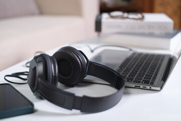 Headset with microphone resting on laptop keyboard, placed on a white desk. Close-up view. Remote work or online learning technology concept.