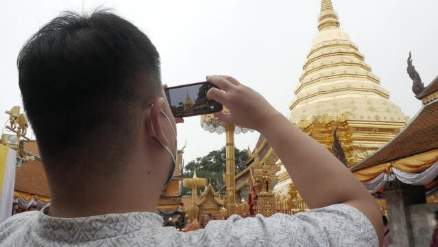 view while an asian man take photo of famous giant golden pagoda among fog cloud natural landscape at Wat Phra That Doi Suthep temple