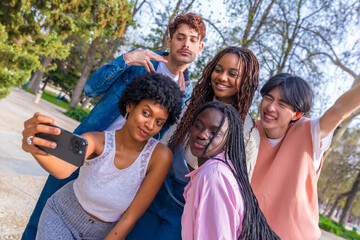 Cheerful multi-ethnic friends taking selfie together in a park