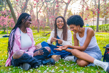 Playful african women messing with flowers sitting on a park