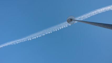 street lamp and the trail of an airplane in the sky