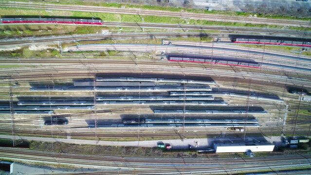 Drone flying slowly sideways over rows of stagnant trains, close to the Copenhagen central station. There are a lot of local and regional trains parked at the facility