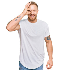 Young irish man wearing casual clothes doing ok gesture with hand smiling, eye looking through fingers with happy face.