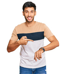 Young handsome man wearing casual clothes in hurry pointing to watch time, impatience, upset and angry for deadline delay - obrazy, fototapety, plakaty