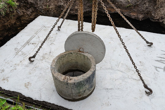 Concrete septic tank with a capacity of 10 m3 located in the garden next to the house, visible cover with manhole.