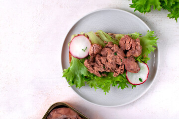 Cod liver served on bread slice with lettuce leaf and radish on the white plate. Exquisite appetizer - 765747509