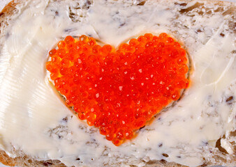 Red caviar served in a heart shape on sandwich with butter