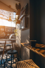 paper cup with hot coffee on table of cozy vintage cafe at morning, sunshine and window
