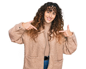 Young hispanic girl wearing winter clothes looking confident with smile on face, pointing oneself...