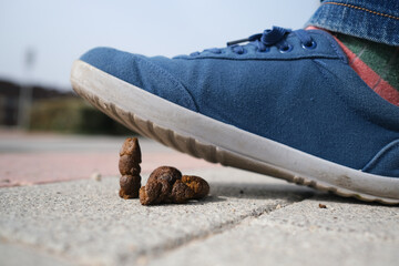 A man with blue snickers steps in dog poop. It is an urban scene and the movement of the city can...