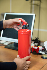 man holds a fire extinguisher in his hands against the background of office equipment.