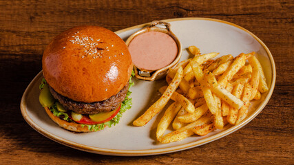 Beef cheeseburger and French fries on plate isolated on wooden background