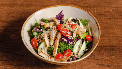 Chicken and vegetables salad bowl on wooden background