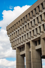 Boston City Hall, the towering, top heavy, brutalist government building on a partly cloudy day.