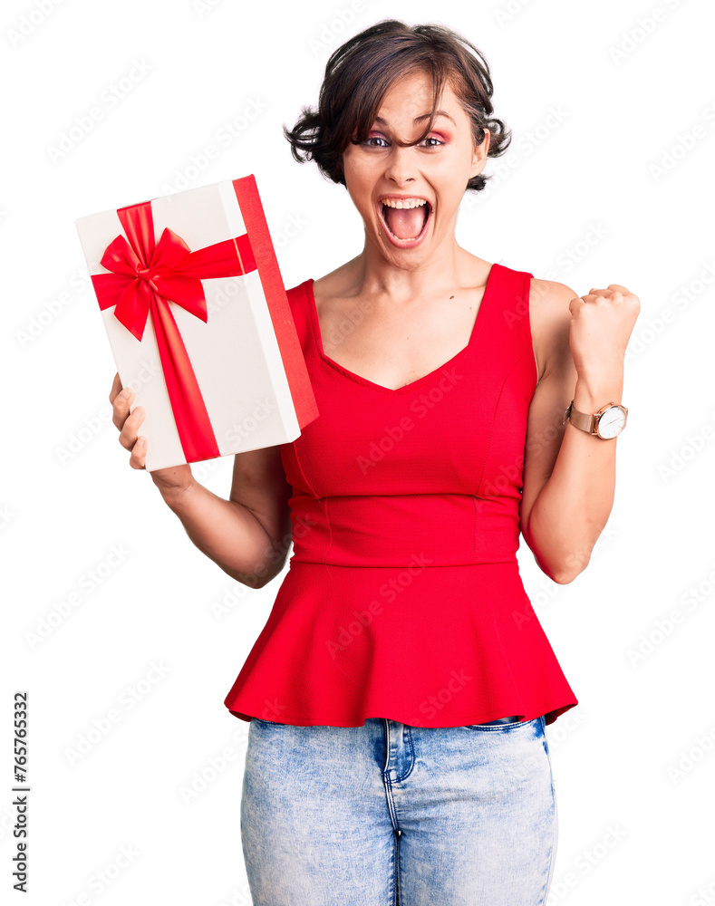 Wall mural beautiful young woman with short hair holding gift screaming proud, celebrating victory and success 