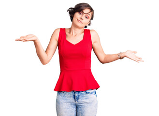 Beautiful young woman with short hair wearing casual style with sleeveless shirt clueless and confused expression with arms and hands raised. doubt concept.