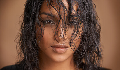 Wet hair, portrait and Indian woman in studio for beauty, wellness or shine cosmetics on brown...