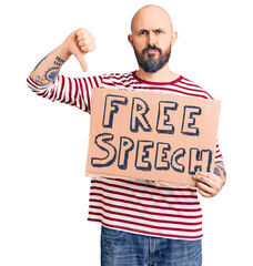 Young handsome man holding free speech banner with angry face, negative sign showing dislike with...