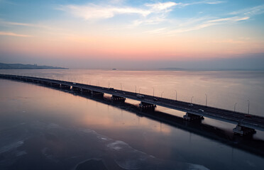 Aerial drone view of low-water bridge across the bay with moving car during the sunset. Active...