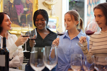 Group of women, multi-ethnic tourists, black Caucasian tourists tasting wine and clinking wine...