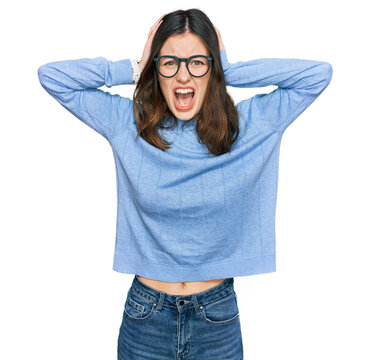 Young beautiful woman wearing casual clothes and glasses crazy and scared with hands on head, afraid and surprised of shock with open mouth