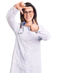 Outdoor-Kissen Young beautiful woman wearing doctor stethoscope and glasses smiling making frame with hands and fingers with happy face. creativity and photography concept. © Krakenimages.com