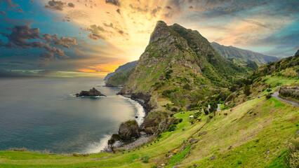 An awe-inspiring sunset over Madeira's rugged coast. Majestic green peaks dominate the foreground...