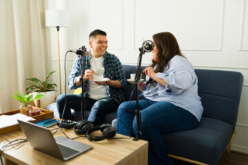 Cheerful happy man laughing with a woman co-host while recording a podcast episode