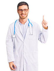 Fototapeta premium Handsome young man with bear wearing doctor uniform showing and pointing up with finger number one while smiling confident and happy.