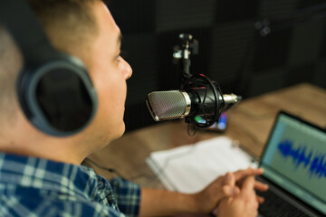 Hispanic podcast host with a laptop recording in the studio