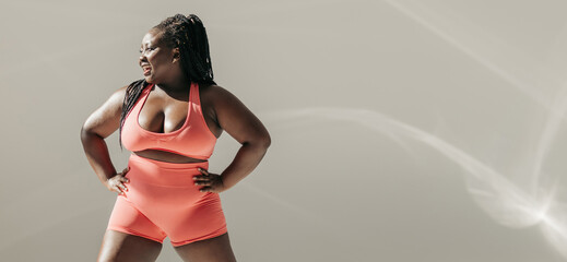 Full length of happy African plus size woman in sportswear warming up before training in fitness studio