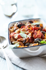 Baked pasta with cherry tomatoes, olives and mozzarella cheese. Bright wooden background. Close up.