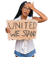 Beautiful hispanic woman holding united we stand banner stressed and frustrated with hand on head, surprised and angry face