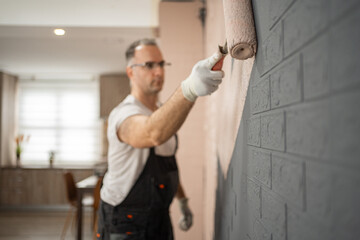 Man in White Shirt and Black Pants Working on a Wall