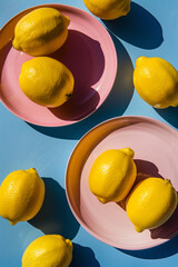 Top view of lemons in pink plates on blue background.Summer concept.