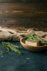 Solid shampoo with rosemary in a wooden plate on a dark background