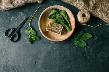 Natural soap with mint in a wooden plate on a dark background