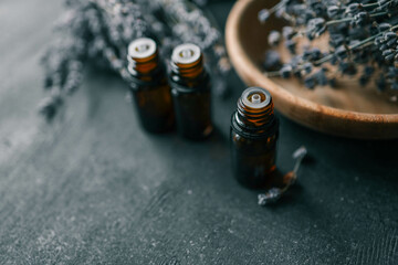 Bottle of essential oil with lavender on wooden background