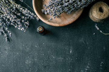 Bottle of essential oil with lavender on wooden background