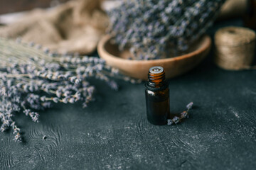 Bottle of essential oil with lavender on wooden background