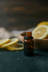 Bottle of essential oil with lemon on wooden background