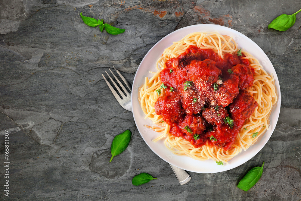 Poster Homemade spaghetti and meatballs with tomato sauce. Above view on a dark stone background.