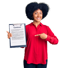 Young african american girl holding clipboard with contract document smiling happy pointing with hand and finger