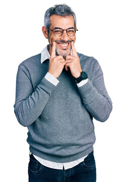 Middle age hispanic with grey hair wearing glasses smiling with open mouth, fingers pointing and forcing cheerful smile
