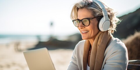 Attractive mature woman 50-60 makes use of laptop on the seashore, active elderly people, Generative AI.