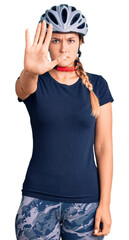 Beautiful caucasian woman wearing bike helmet doing stop sing with palm of the hand. warning expression with negative and serious gesture on the face.