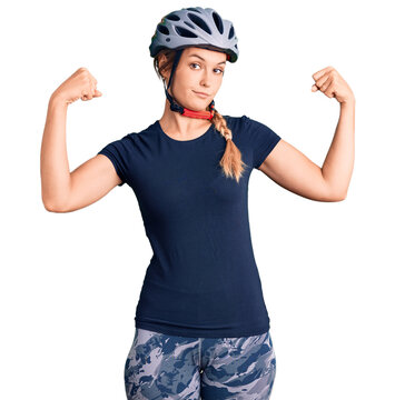 Beautiful caucasian woman wearing bike helmet showing arms muscles smiling proud. fitness concept.